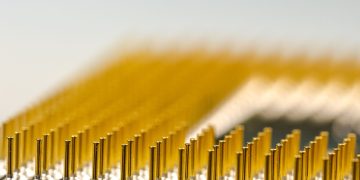 Detailed macro shot of a CPU microchip with focus on golden pins, highlighting technology details.
