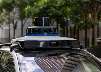 Detailed view of sensors atop an autonomous car, showcasing advanced technology in an urban setting.