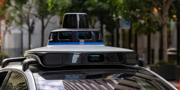 Detailed view of sensors atop an autonomous car, showcasing advanced technology in an urban setting.