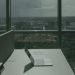 Laptop on office desk with a city skyline through a large window, offering a modern workspace view.