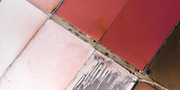 Vibrant aerial view of geometric salt ponds in varied red and pink hues.