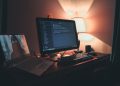 Warmly lit home office with dual screens for coding and programming. Perfect modern workspace for tech enthusiasts.