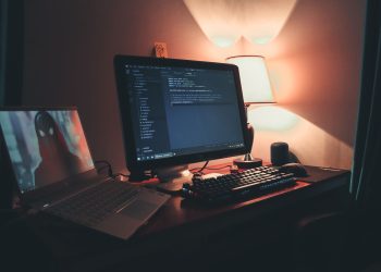 Warmly lit home office with dual screens for coding and programming. Perfect modern workspace for tech enthusiasts.