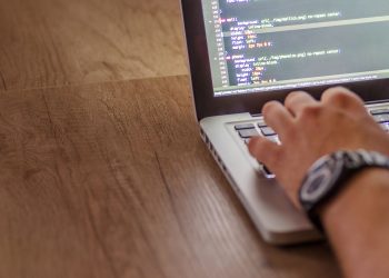 Close-up of a person coding on a laptop, showcasing web development and programming concepts.