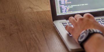 Close-up of a person coding on a laptop, showcasing web development and programming concepts.