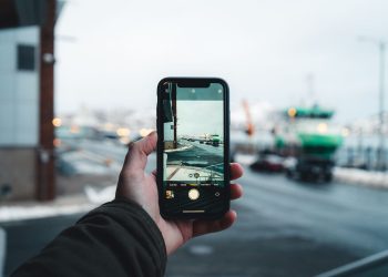 Person captures an urban winter scene on a smartphone, focusing on the street view ahead.