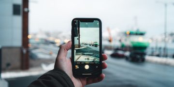 Person captures an urban winter scene on a smartphone, focusing on the street view ahead.