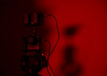 Minimalist close-up of a camera setup in dramatic red lighting, perfect for creative photography projects.