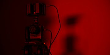 Minimalist close-up of a camera setup in dramatic red lighting, perfect for creative photography projects.
