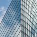 A sleek glass skyscraper reflecting the blue sky and clouds, showcasing modern architectural design.