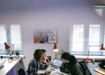 A group of people discussing ideas around laptops in a bright, modern office space.