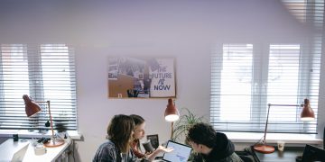 A group of people discussing ideas around laptops in a bright, modern office space.