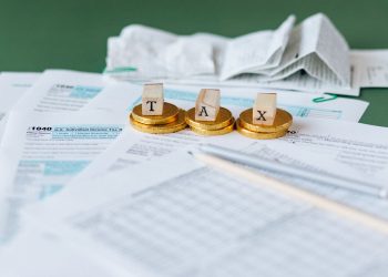 세금 신고서와 동전 위에 놓인 TAX 글자 블록