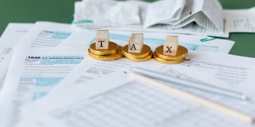 세금 신고서와 동전 위에 놓인 TAX 글자 블록