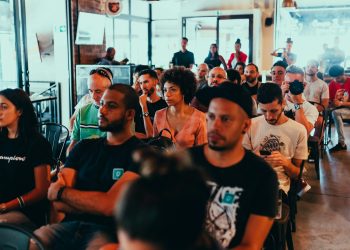 A diverse group of adults attentively participating in an indoor seminar or conference.