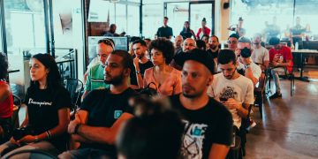 A diverse group of adults attentively participating in an indoor seminar or conference.
