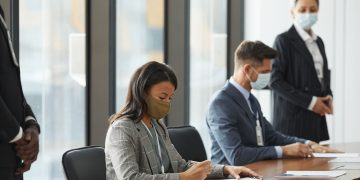 Professionals in face masks having a business meeting in a modern conference room.