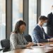 Professionals in face masks having a business meeting in a modern conference room.