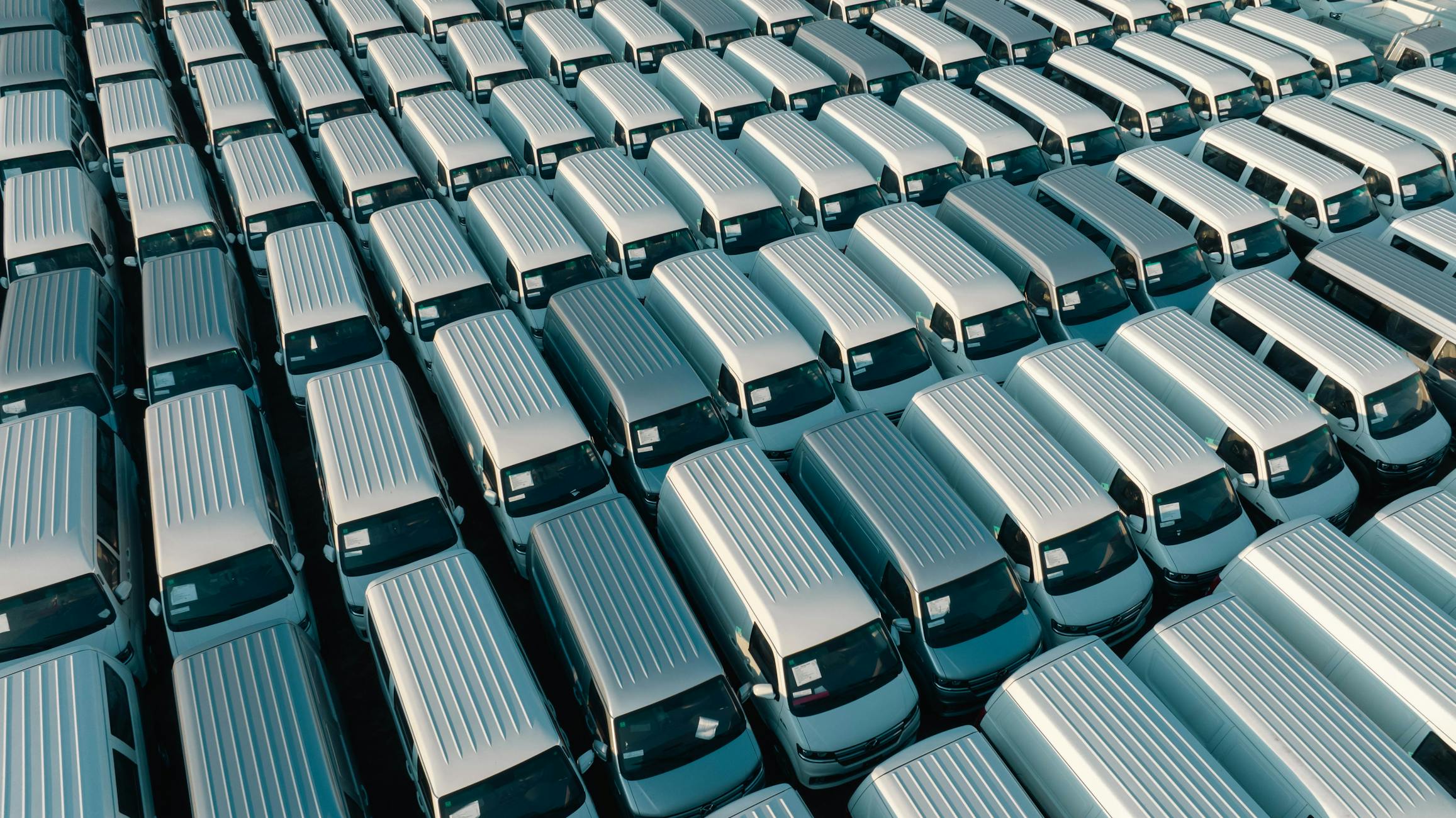 An aerial shot of a large fleet of white vans parked in rows under the early morning light in Libya.
