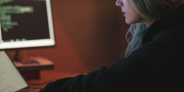 어두운 방에서 코드 화면을 보며 작업하는 개발자