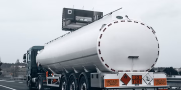 Rear view of a large tanker truck transporting fuel on a highway, emphasizing logistics and transportation.
