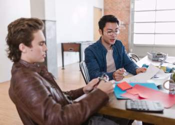 Two young entrepreneurs brainstorm ideas in a modern office setting, fostering innovation and collaboration.