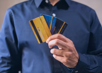 Person holding three credit cards, symbolizing finance, security, and e-commerce.