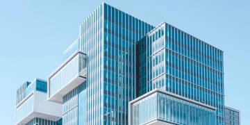 Striking contemporary glass building with unique geometric extensions under clear blue sky.