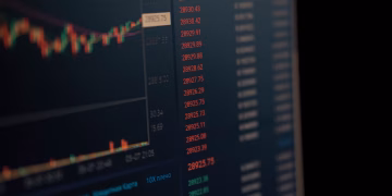 Close-up of a computer screen showing dynamic financial market data and charts, indicating real-time trading updates.