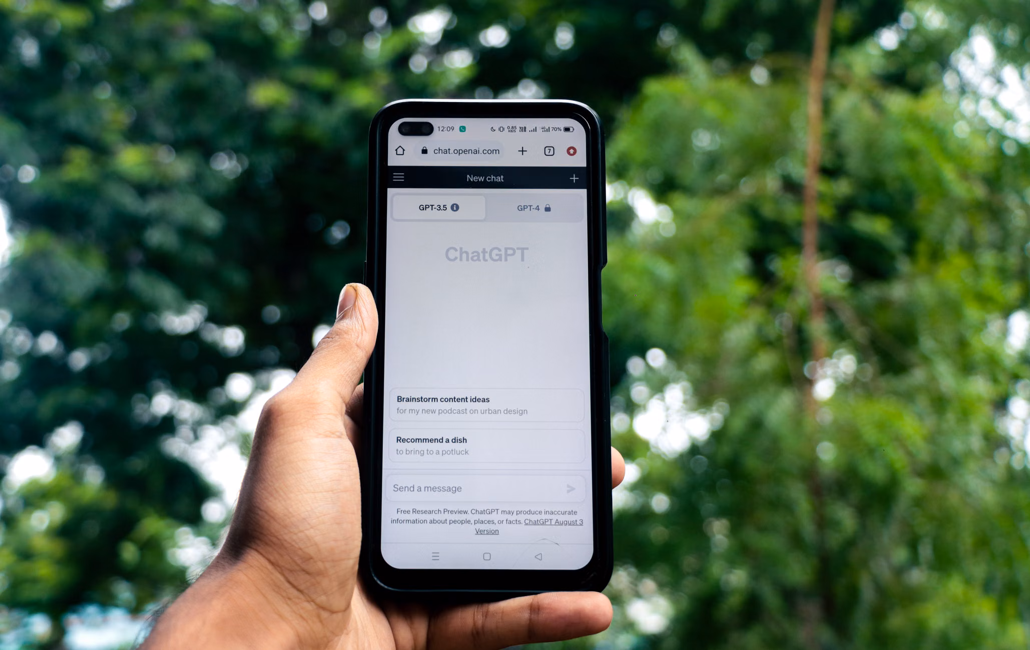 Close-up of a hand holding a smartphone displaying ChatGPT outdoors.