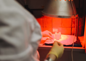 A scientist carefully handles samples in a lab under infrared light, reflecting precision and safety.