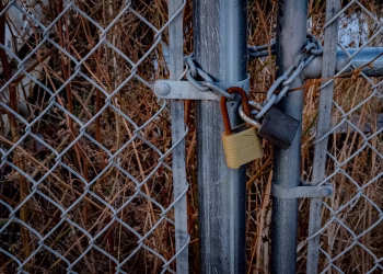 A close-up of a chain link fence with padlocks securing it, symbolizing high security outdoors.