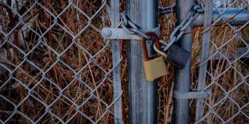 A close-up of a chain link fence with padlocks securing it, symbolizing high security outdoors.