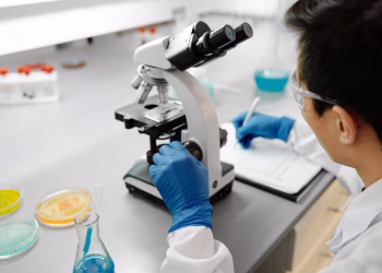 Scientist using a microscope to analyze samples in a modern laboratory environment.