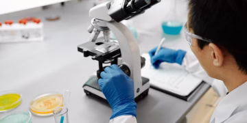 Scientist using a microscope to analyze samples in a modern laboratory environment.