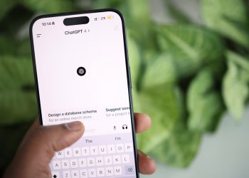 Hand holding smartphone displaying ChatGPT interface, surrounded by greenery.
