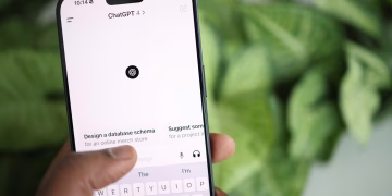Hand holding smartphone displaying ChatGPT interface, surrounded by greenery.
