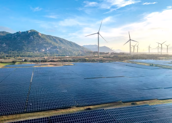Aerial view of a solar and wind energy farm set against Vietnam's scenic landscape.
