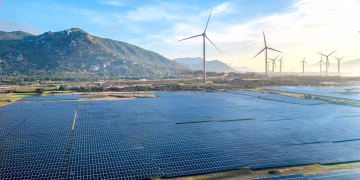 Aerial view of a solar and wind energy farm set against Vietnam's scenic landscape.