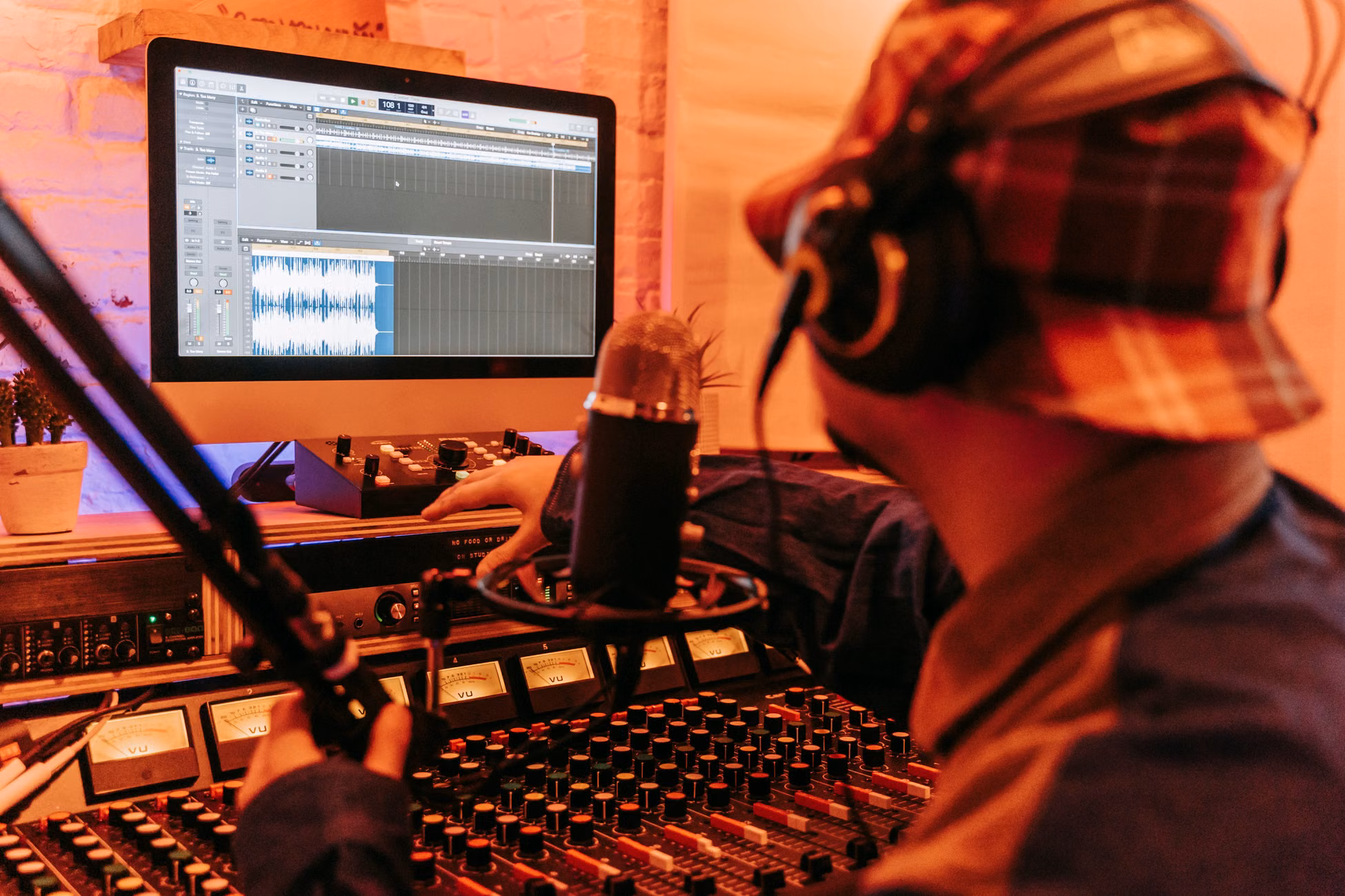 Music producer working in a studio with computer and mixing equipment.