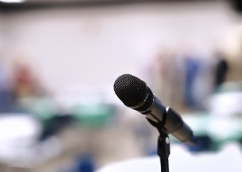 A microphone stands on a stand in an empty room.