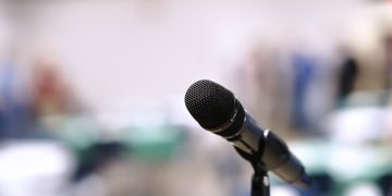 A microphone stands on a stand in an empty room.