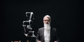 A bearded man in suit playing chess with robotic arm, showcasing AI strategy.