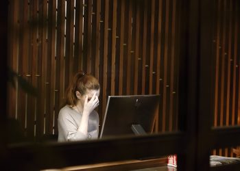 a woman sitting in front of a laptop computer