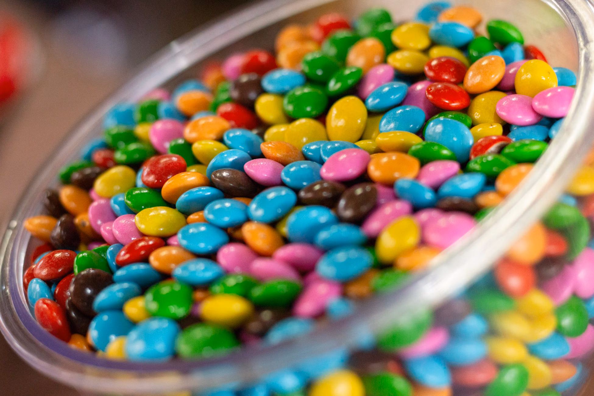 A glass bowl filled with colorful candy-coated chocolates, perfect for a festive party setting.