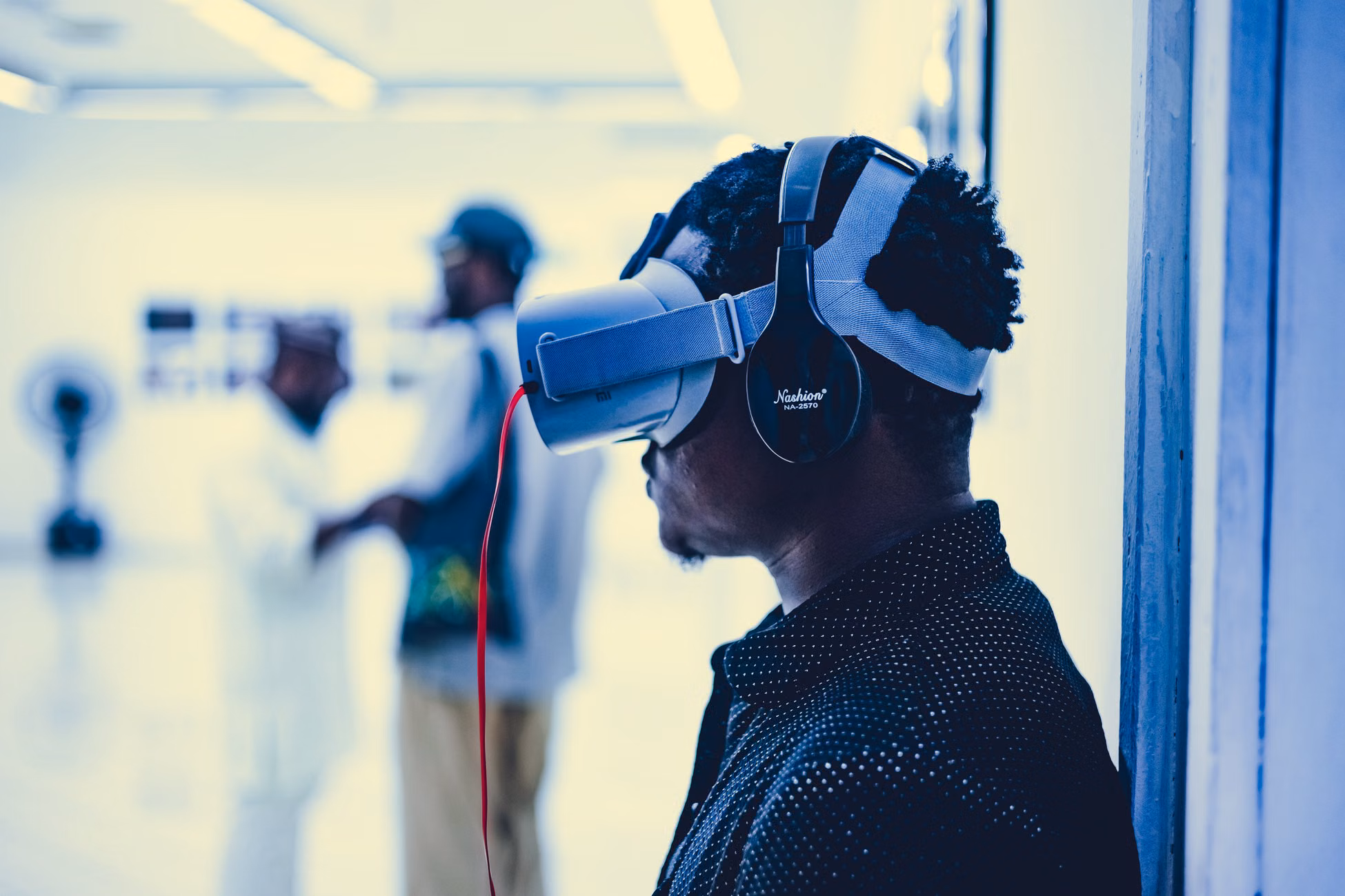 Profile of a man using VR headset indoors with blurred background.
