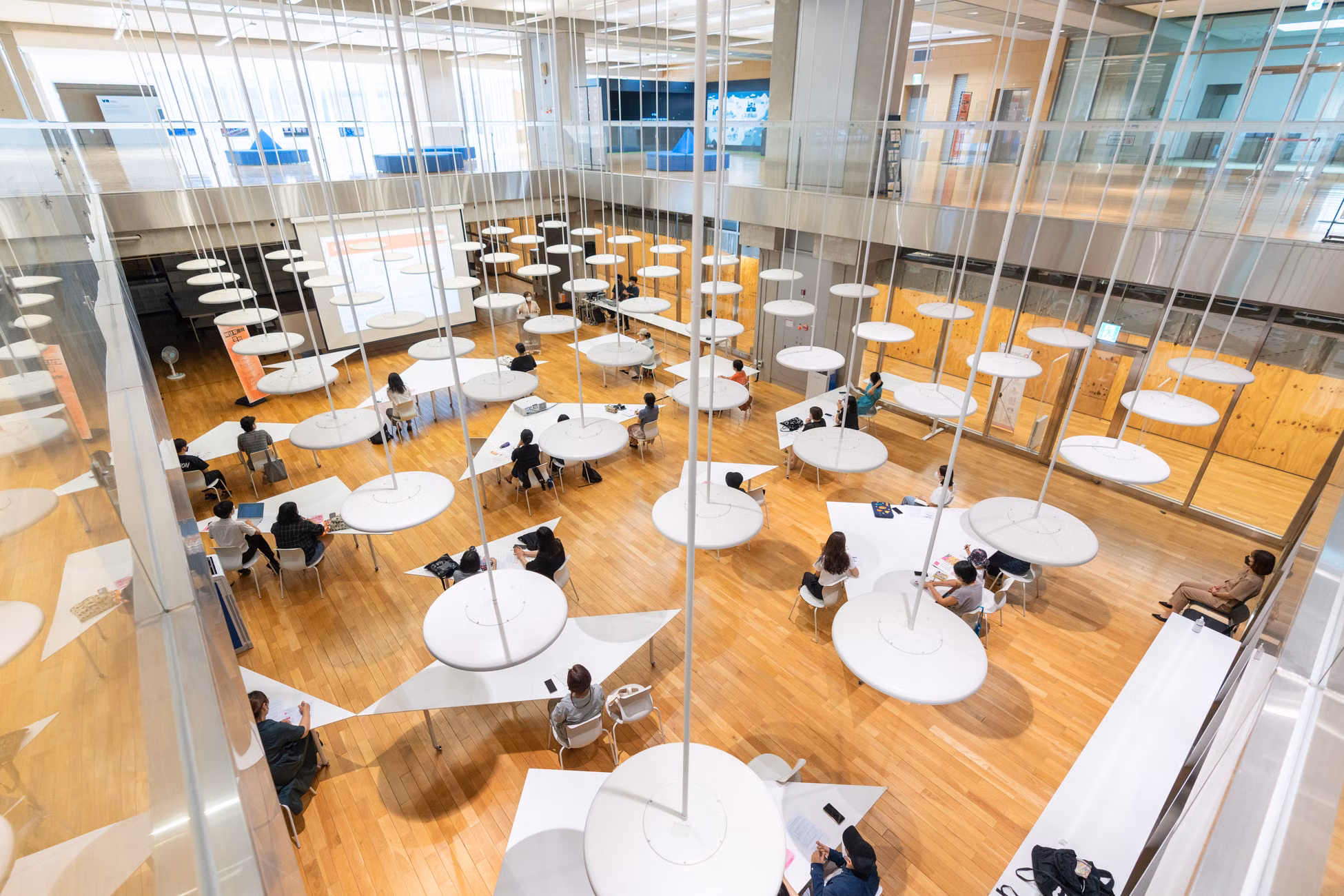 Aerial view of a contemporary study hall with unique circular tables and seated individuals.