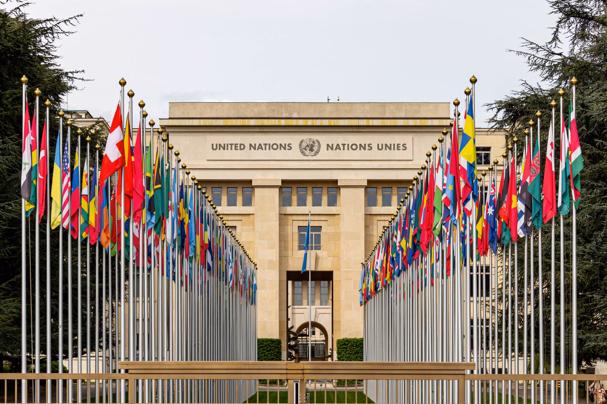 View of the United Nations Office in Geneva adorned with flags of various countries.
