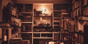 A warmly lit home library filled with a diverse collection of books and a cozy atmosphere.