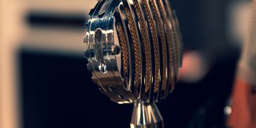 Close-up of a vintage condenser microphone in a recording studio with a focus on intricate details.